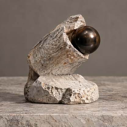 Angled ivory-toned cradle sculpture holding a glossy dark brown orb above an irregular base, without text overlay